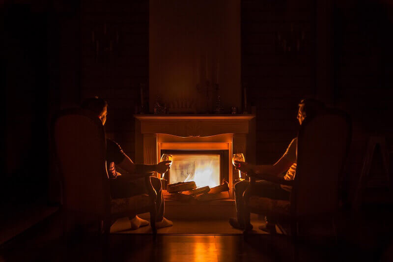 two people sitting in from of a fireplace