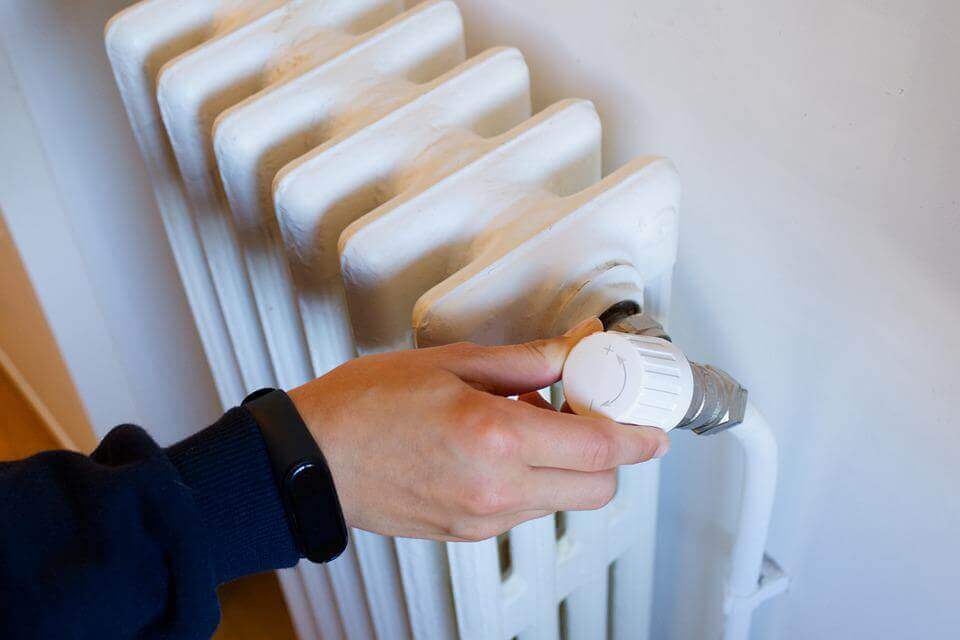 A person adjusting a radiator