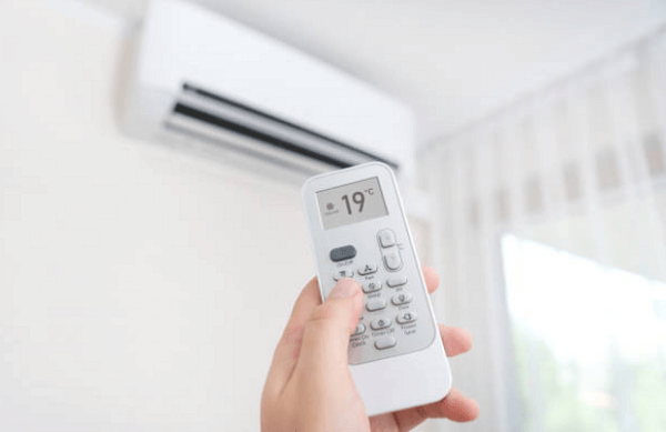 A person adjusting the temperature of an AC using a remote