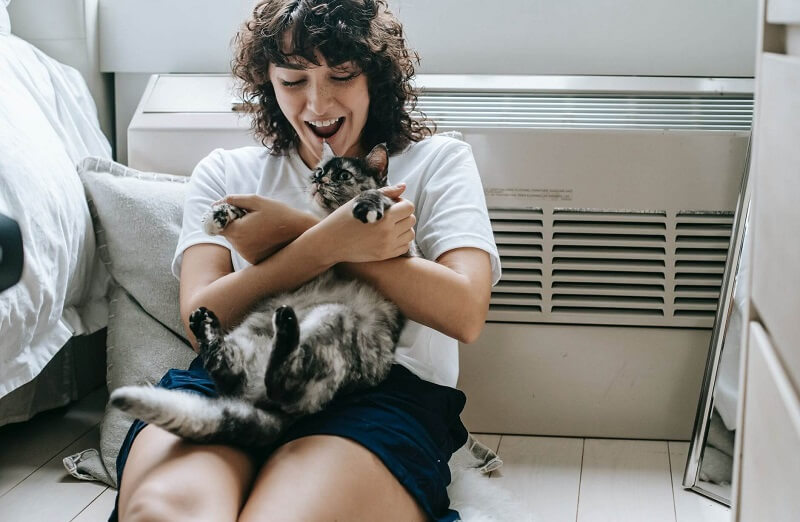 A woman happily playing with her cat 